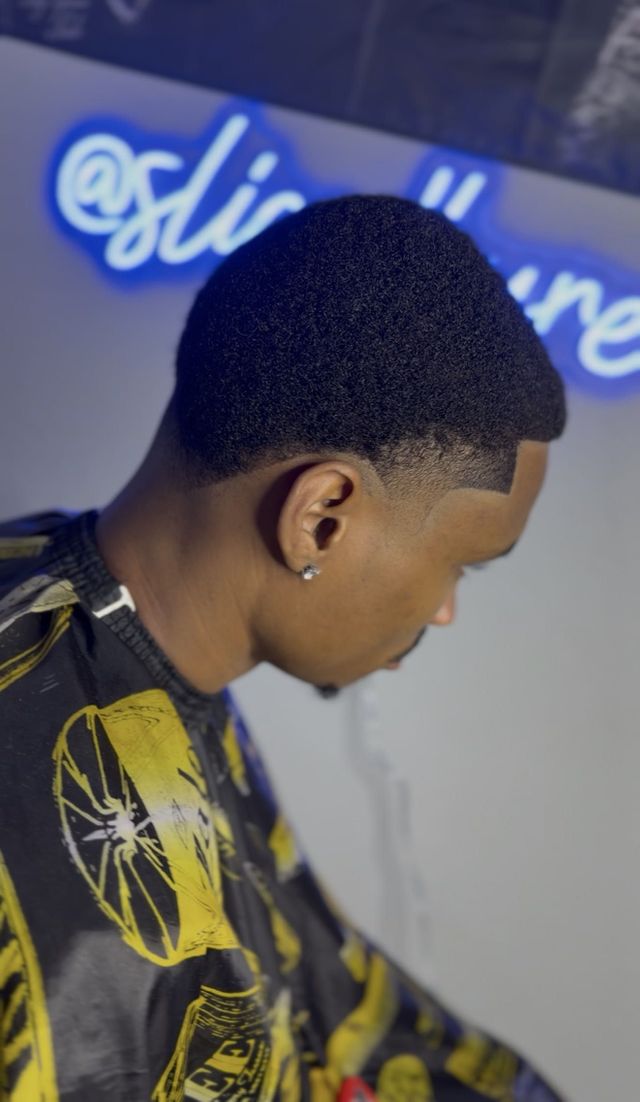 Side profile of a real client with a short textured top, sharp taper fade and precise lineup